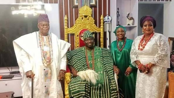 The Olobu receiving visitors on the throne, in green aṣọ-oke and coral.